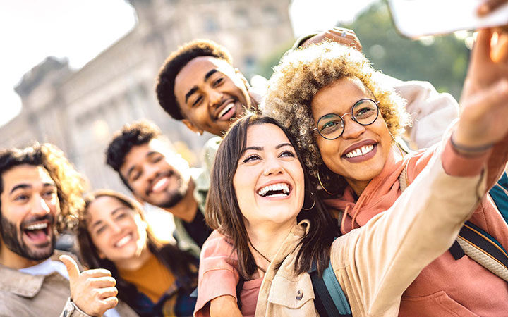 A group of young men and women take a selfie together.