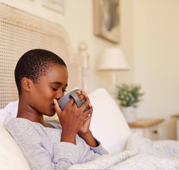 A woman relaxes in bed with a comforting mug of tea, unwinding after a stressful day.